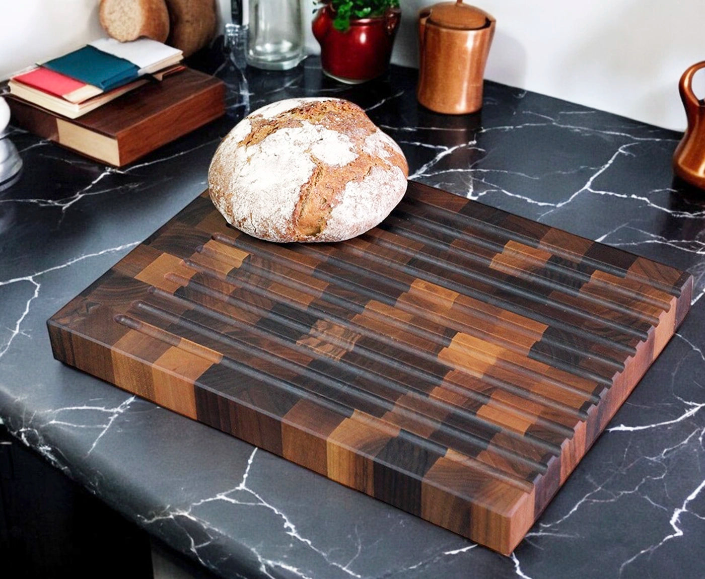 Brotschneidebrett Stirnholz Nussbaum mit Rillen und Brotlaib auf Küchenzeile.