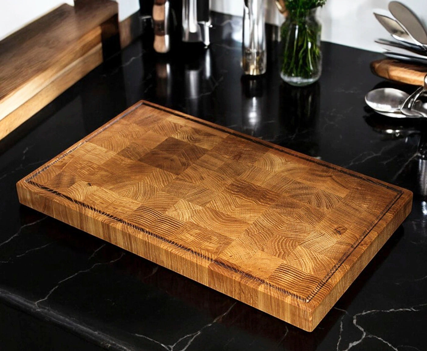 Stirnholz Schneidebrett Eiche mit Saftrille auf schwarzer Küchenzeile.