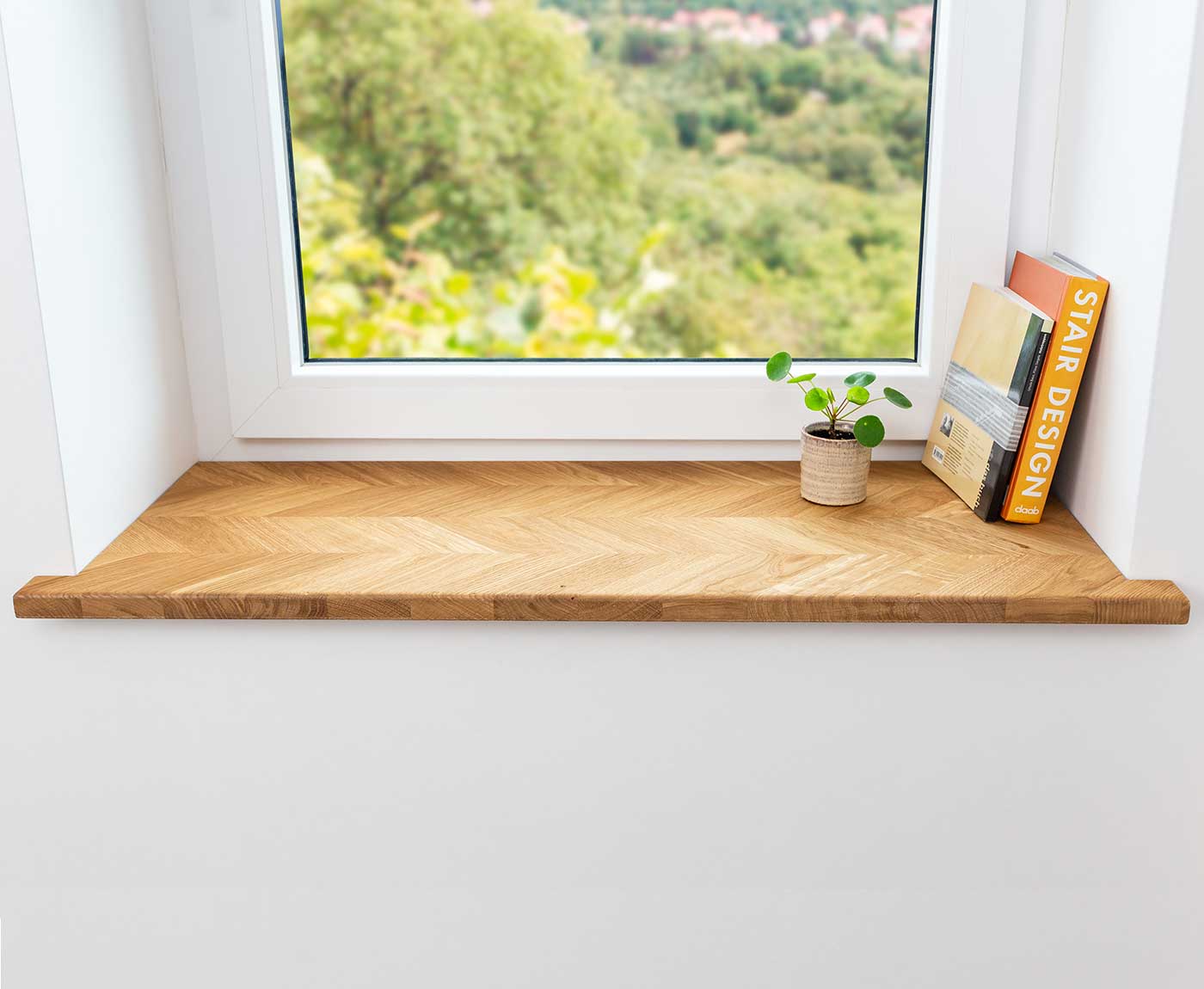 Fensterbank Fischgrät im Fensterrahmen, dekoriert mit Pflanze und Büchern.