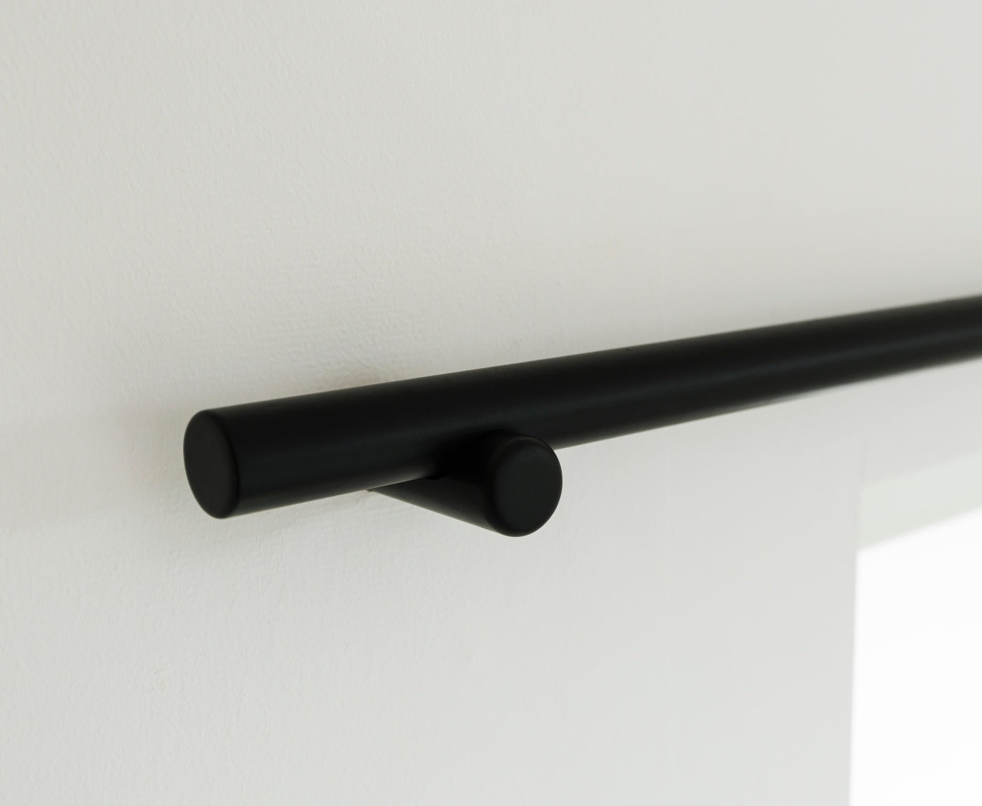 Nahaufnahme von Gardinenstange schwarz mit Halterung, aus Massivholz 