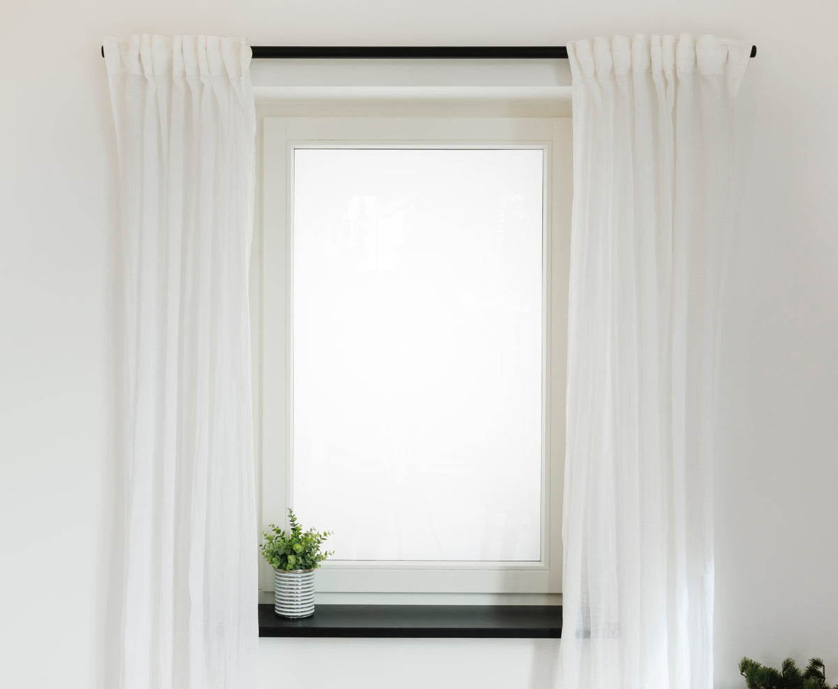 Fenster mit schwarzer Gardinenstange und Fensterbrett, mit Pflanzen und weißen Vorhängen