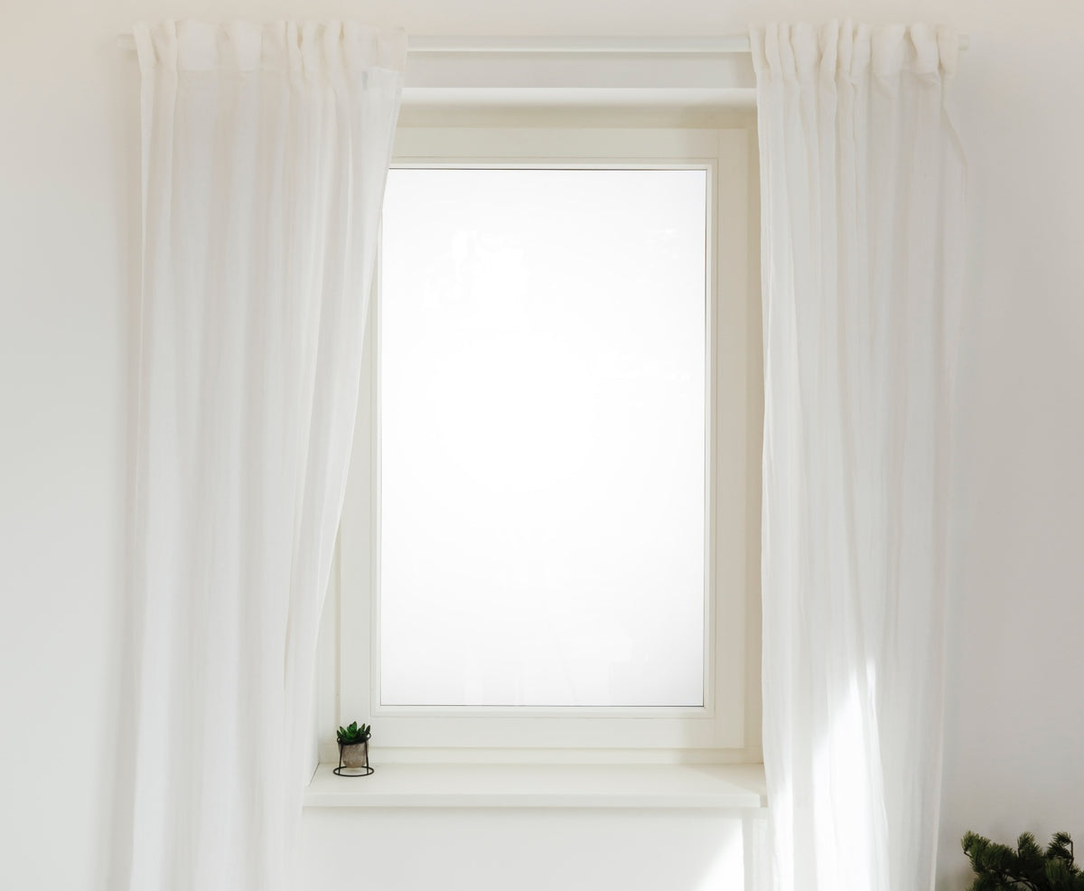 Fenster mit weißer Gardinenstange, weißen Gardinen und Pflanzen