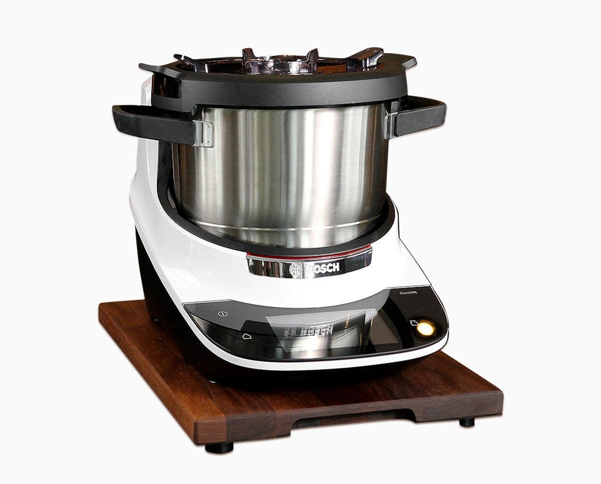 Gleitbrett aus Nussbaum mit Griffmulde und Bosch Cookit vor weißem Hintergrund.