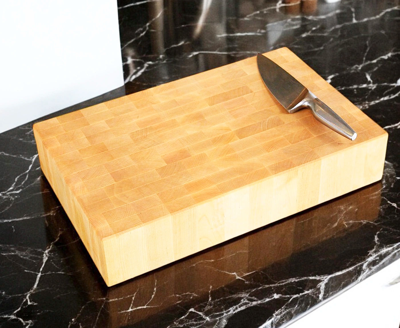 Hackblock in Stirnholz Birke mit Edelstahlmesser auf schwarzer Küchenzeile.