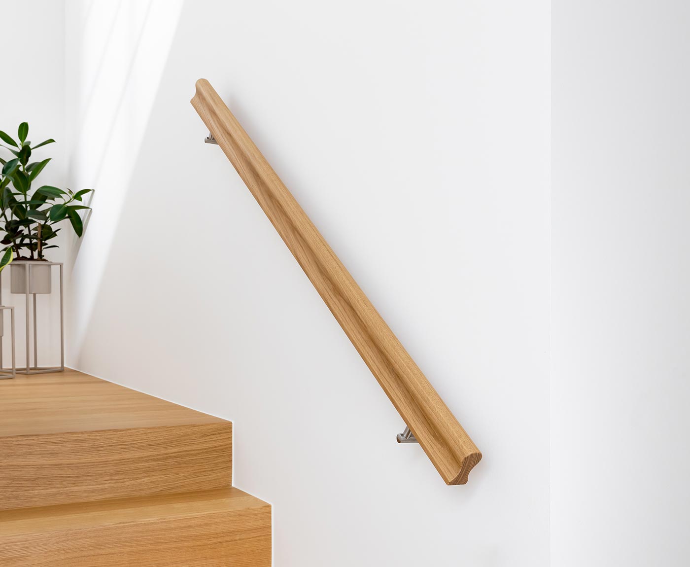 Handlauf Eiche in Omega, mit Edelstahlhaltern an weißer Wand montiert - passend zur Holztreppe.