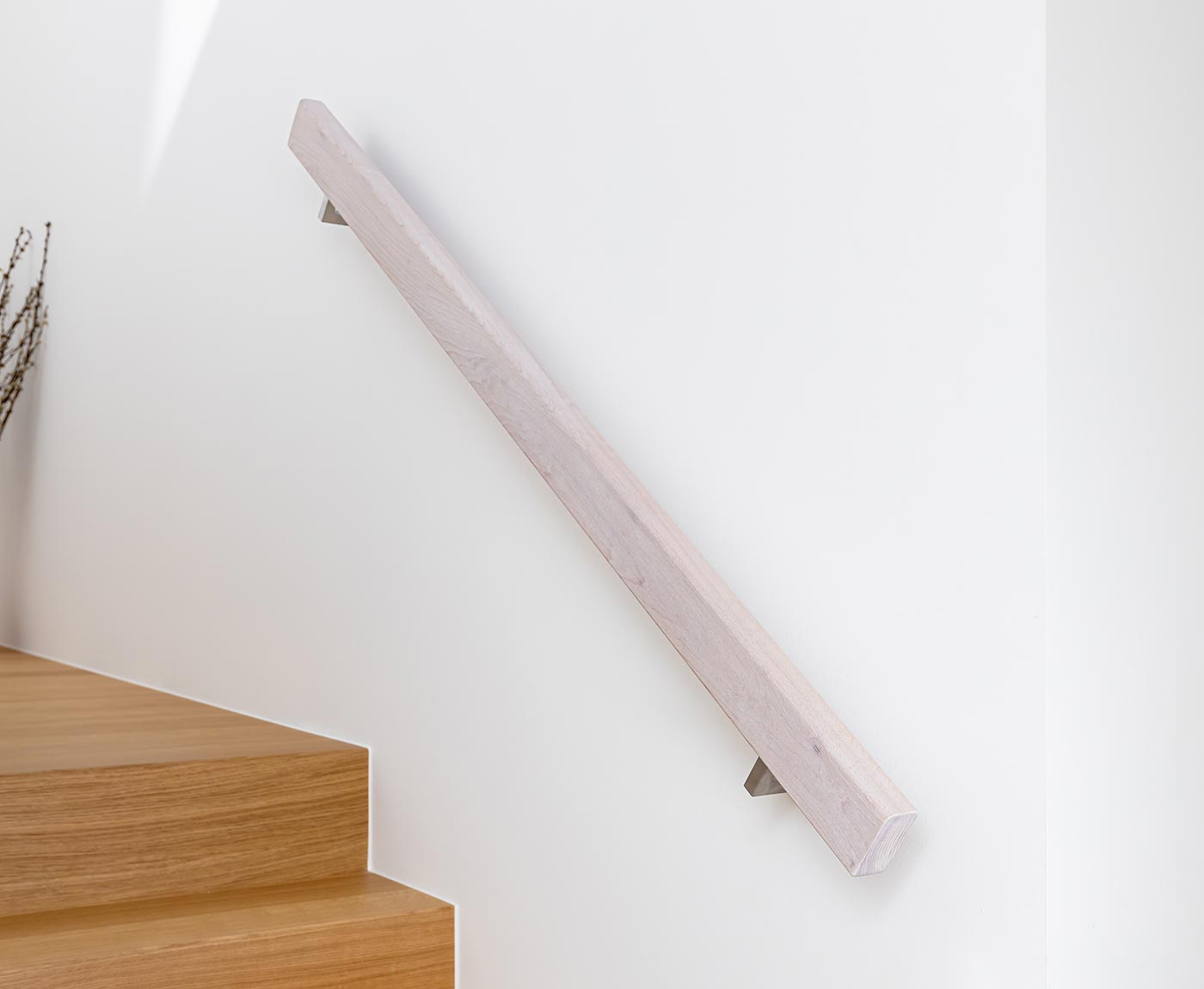 Rechteckiger Handlauf aus Holz in weiß, mit Edelstahl-Haltern an weiße Wand montiert.