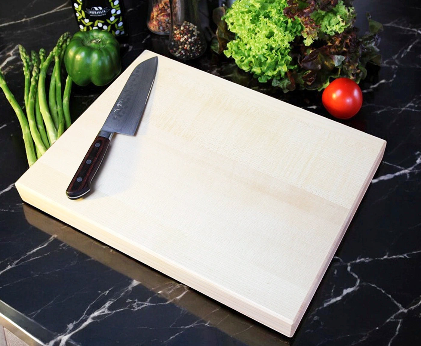 Helles Küchenbrett Holz aus Birke mit Messer und Gemüse als Dekoration.