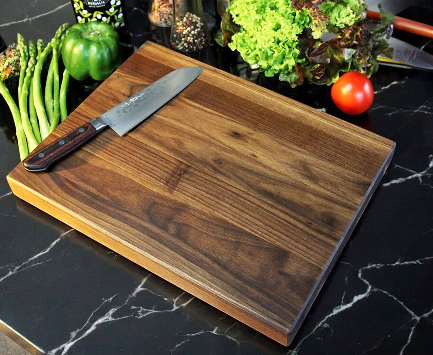 Küchenbrett Holz Nussbaum mit Messer und Gemüse als Dekoration, auf Küchenzeile.