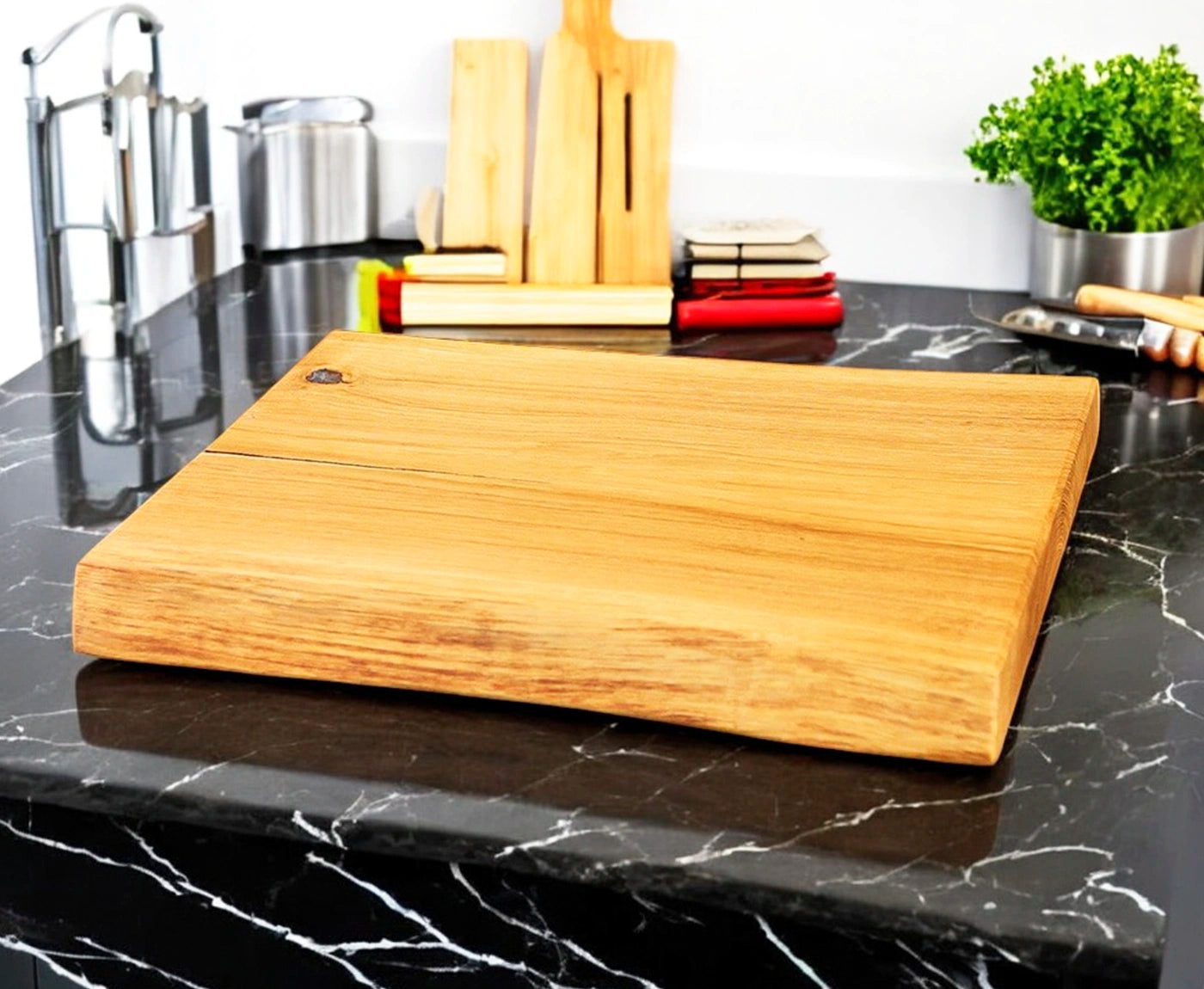 Holz Schneiderbrett in Eiche auf Arbeitsplatte mit Küchenutensilien im Hintergrund.