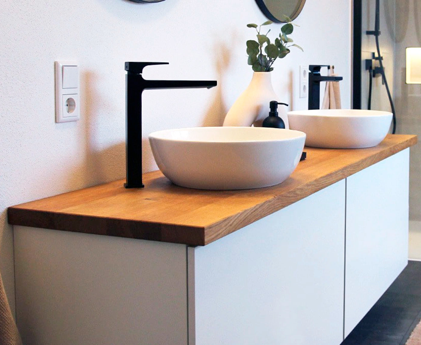 Seitliche Aufnahme von Waschtisch mit zwei Becken und Waschtischplatte aus Holz.