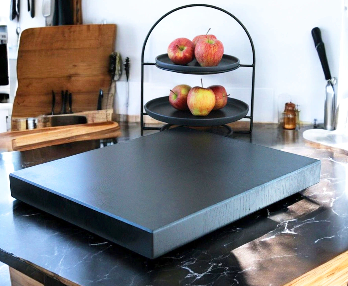 Schwarzes Stirnholz Schneidebrett auf Arbeitsplatte mit Küchenutensilien.